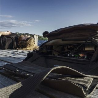 Man laying down wearing headphones plugged into audio recorder